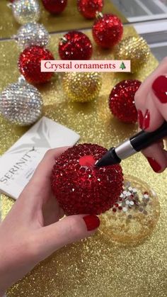 a person with red nail polish is holding a heart shaped object in front of some glitter balls