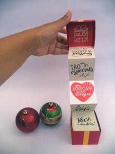 a hand is holding an ornament in front of two boxes