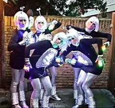 four women dressed in silver and black posing for the camera