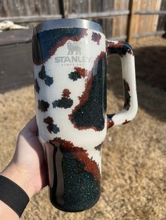 a hand holding a coffee mug with black, red and white designs on the outside