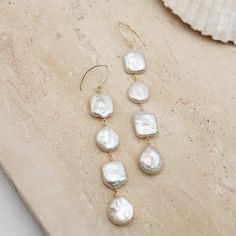 Perfect for adding a touch of elegance to any outfit. Crafted with high-quality luster pearls in both coin and square styles, these earrings radiate beachy and wedding vibes. Each pearl is meticulously hand-wrapped in 14K gold-filled wire, ensuring both beauty and durability. Elevate your summer style or accessorize for special occasions with these gorgeous dangles. - 14K Gold Filled- Freshwater Pearls- Coin and Square Styles Wedding Vibes, Hand Wrap, Summer Style, Fresh Water, Freshwater Pearls, Gold Filled, Special Occasion, Coin, Summer Fashion