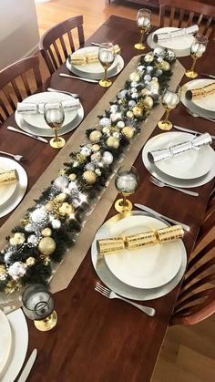 the table is set with silver and gold plates, silverware, and christmas decorations