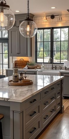 a large kitchen with marble counter tops and gray cabinets