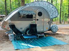 an rv is parked in the woods with its awning open