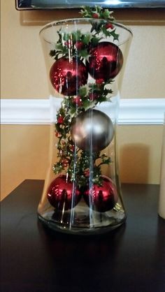 a glass vase filled with ornaments on top of a table