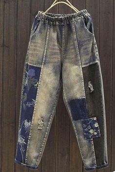 an old pair of jeans with patches on them hanging from a hanger against a wooden wall