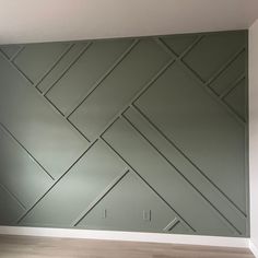 an empty room with wood flooring and green paneled wall covering the entire area