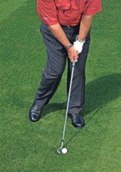 a man in red shirt and black pants playing golf on green field with white ball