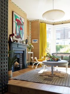 a living room with yellow curtains and a fire place in the middle of the room