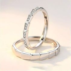 two white gold wedding rings with diamonds on each one, set against a plain background