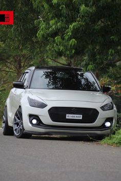 a white car is parked on the side of the road next to some bushes and trees