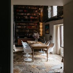 a dining room table and chairs in front of a bookshelf filled with books