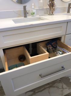 an open drawer in the middle of a bathroom sink