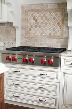 a stove top oven sitting inside of a kitchen next to white cabinets and counter tops