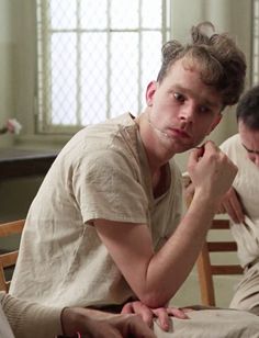 two young men sitting in chairs with one holding his hand to his chin and the other looking at him