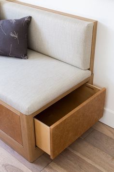 a couch with drawers underneath it and a pillow on the backrest, in front of a white wall