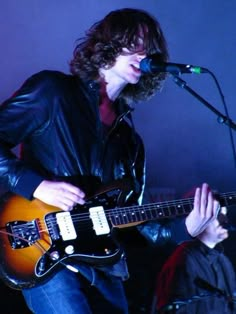 a man playing an electric guitar in front of a microphone