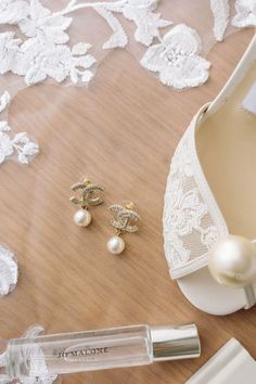 a pair of white shoes next to a bottle of perfume and pearls on a table