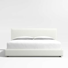 a bed with white sheets and pillows on it