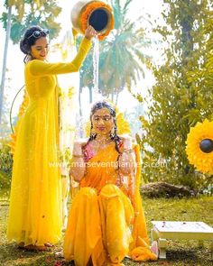 two women dressed in yellow are playing with each other and having water thrown on them