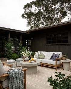 an outdoor living area with couches, tables and plants on the side of the house