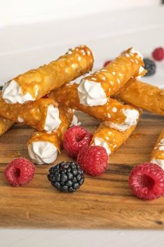 some food is laying out on a cutting board with raspberries and blackberries