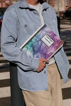 a man is holding a book in his hands while standing next to a crosswalk