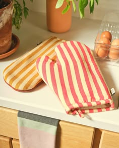 two kitchen towels sitting on top of a counter next to an egg in a bowl