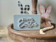 a wooden sign that says happy easter sitting on top of a table next to other decorations