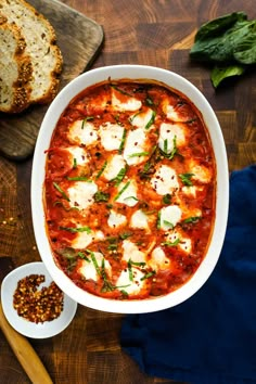 a white bowl filled with tomato sauce and mozzarella bread on top of a wooden cutting board