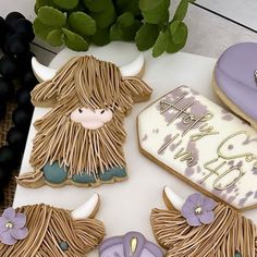 decorated cookies are displayed on a table with purple flowers and other decorative items in the background