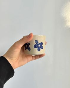 a hand holding a cup with blue flowers on it