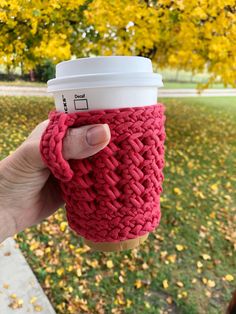 a person holding up a coffee cup in their hand