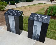 two black and white photographs on display in front of a park with people walking by