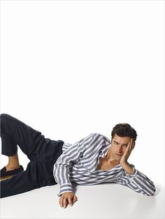 a man laying on the ground with his hand to his face while wearing a striped shirt and pants