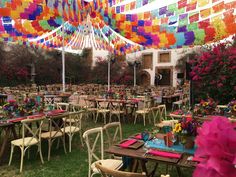 an outdoor dining area with tables and chairs covered in multicolored paper