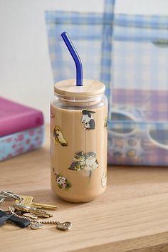 a jar with a blue straw sitting on top of a table next to some keys