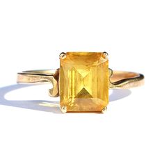 "Vintage estate yellow sapphire 10K gold ring. Size 6.75. Emerald cut genuine sapphire gemstone with a stunning golden yellow color. Four prong solitaire setting with asymmetrical scroll design on the shoulders. Simple and classic design. Signed with \"Kohinoor\" hallmark and stamped 10K for solid gold fineness on interior of band. Acquired from a private estate collection. Excellent pre-owned condition." Golden Yellow Color, 10k Gold Ring, Yellow Sapphire, Sapphire Gemstone, Vintage Yellow, Emerald Cut, 10k Gold, Gold Style, Solitaire Ring