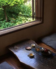 a wooden table topped with two bowls of food next to a window filled with green plants