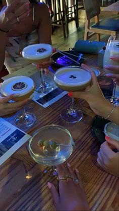 several people sitting at a table holding up wine glasses with drinks in them and plates on the table