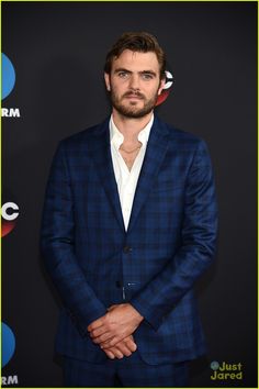 a man in a blue suit and white shirt is posing for the camera at an event