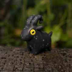 a small black animal with yellow eyes sitting on a wooden surface