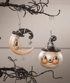 two halloween decorations hanging from a tree branch