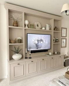 a living room filled with furniture and a flat screen tv on top of a wooden shelf