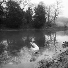 black and white photograph of a woman kneeling in the water