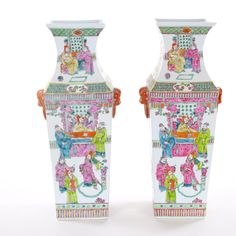 two colorful vases sitting next to each other on a white surface with people painted on them