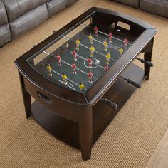 a coffee table with foosball on it in a living room area next to a couch