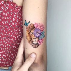 a woman's arm with a lion and flowers tattoo on it