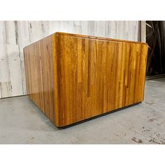 a large wooden cabinet sitting on top of a cement floor next to a wall with white paint