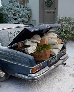 an old car is loaded with boxes and presents in the snow, while it's parked outside